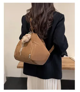 Back view of a woman wearing a stylish brown triangular backpack with a plush bear pendant.