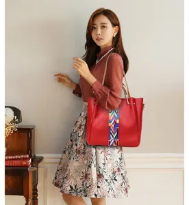 Asian model elegantly posing with a stylish red leather tote bag featuring a colorful strap