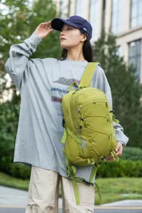 Model carrying a lime green lightweight hiking backpack in an outdoor urban garden setting