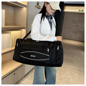 Vue détaillée du grand sac de voyage noir montrant un tissu résistant et des poches zippées.