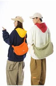 Models wearing large orange and sage green crossbody dumpling bags for casual travel.