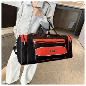 Détail de grand sac de voyage sport, tissu noir et rouge résistant avec multiples poches pratiques.