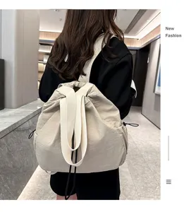 Detail shot of a casual nylon drawstring backpack worn in a modern indoor corridor setting.
