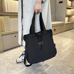 Detailed view of the black nylon casual backpack with drawstring and shoulder straps.