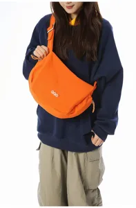 Vibrant orange crossbody dumpling bag shown on model for casual and sporty everyday use.