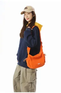 Vibrant orange crossbody dumpling bag shown on model, large capacity for daily travel.