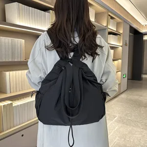 Detail view of casual black nylon drawstring backpack worn on back, soft fabric daily commuter bag.