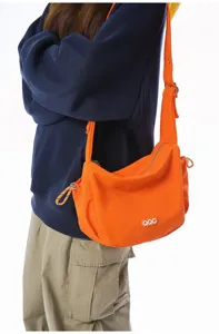 Vibrant orange crossbody dumpling bag shown being worn for casual everyday style.