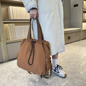 Detail view of casual brown nylon backpack featuring drawstring closure and sturdy straps.