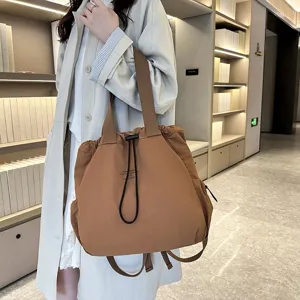 Closeup view of the casual brown nylon backpack featuring a drawstring closure and sturdy straps.