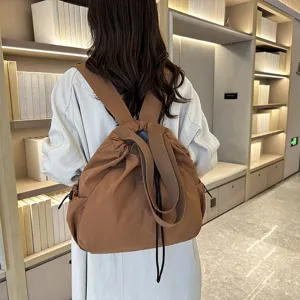 Detail view of casual brown nylon backpack, drawstring closure, wide strap, minimalist daily use.