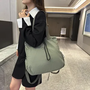 Detailed view of casual nylon backpack worn by model in a modern indoor hallway setting.