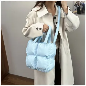 Stylish light blue puffer quilted tote bag shown in a lifestyle shot with a white coat