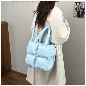 Large capacity light blue quilted padded tote bag carried by a woman in a long coat.
