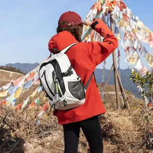 Back view of woman with red jacket wearing white outdoor hiking backpack on mountain trail