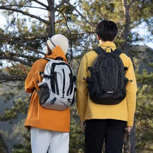 Couple wearing gray and black outdoor hiking backpacks in a scenic forest.