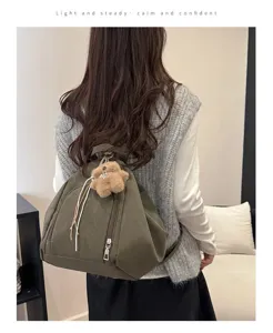 Back view of a woman wearing a dark green minimalist backpack with a plush bear