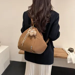 Stylish brown large capacity triangle backpack for women featuring a cute plush bear charm