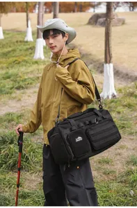 Vue détaillée du sac de voyage noir multifonctionnel porté par le modèle en plein air.
