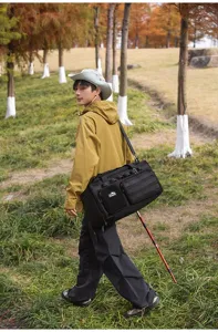 Sac de voyage de grande capacité de couleur noire présenté dans un beau décor de parc.