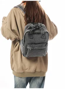 Back view of a retro washed denim mini backpack on a model wearing a casual hoodie