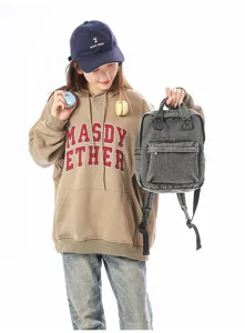 Compact washed denim backpack in retro forest style shown being held by a model