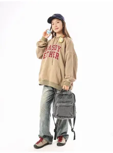 Asian model holding a vintage washed denim backpack in a minimalist casual studio