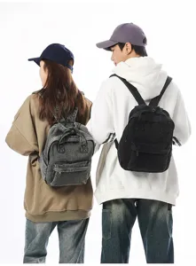 Back view of models wearing vintage grey washed denim and black canvas mini backpacks