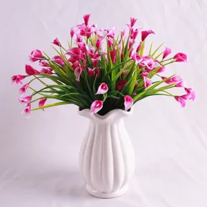 Detailed view of magenta artificial calla lily flowers in a decorative white ceramic vase