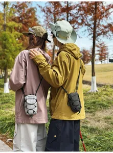 Tactische mini crossbodytas voor telefoonopslag met modellen in een herfstpark