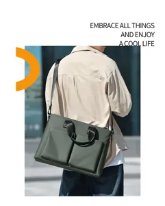 Detailed view of dark green men's business briefcase in urban scene, showing front pockets.