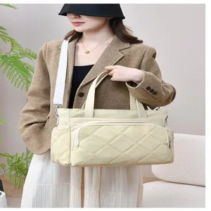 Detail view of a large capacity quilted canvas tote bag with multi pockets and white straps.