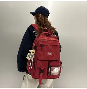 Detailed view of red camouflage student backpack with bear pendant and multi pockets.