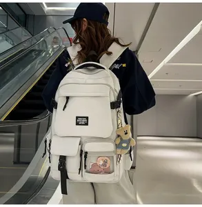 Detailed shot of a stylish white campus backpack with multiple pockets and a cute bear pendant.