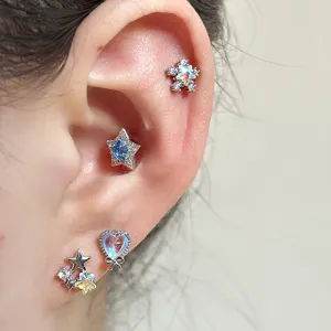 Macro detail of sparkling sea blue zircon star and heart earrings worn on a human ear
