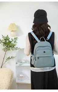 Back view of minimalist textured blue backpack worn by a model in a cozy interior setting.