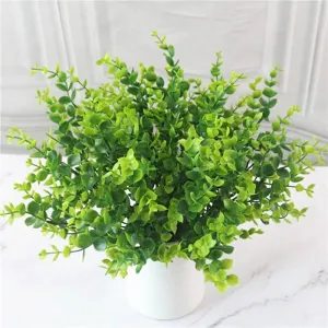 Detailed view of vibrant green artificial eucalyptus stems in a white modern pot.