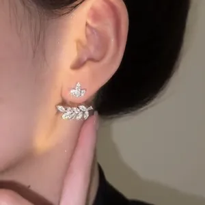 Vista detallada de pendientes de circonita con forma de espiga de trigo usados por una modelo