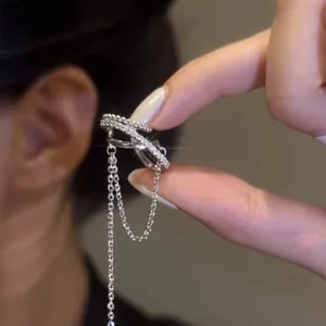 Macro detail of a sparkling silver-plated zircon ear cuff with hanging chains