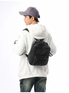 Back view of a black washed denim mini backpack worn with a white hoodie