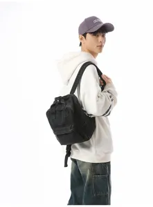 Model wearing a black vintage washed denim mini backpack against a white background.