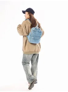 Casual washed denim small backpack for women worn by model in a professional studio setting