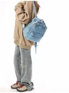 Lifestyle side view of a vintage light blue washed denim small backpack for casual daily use