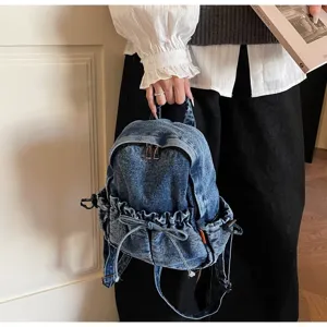 Vue détaillée du sac à dos en denim élégant doté d'une poche avant avec cordon de serrage.