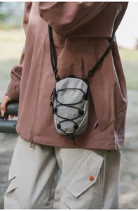 Detailweergave van een grijze tactische crossbody telefoontas met ruitjespatroon.
