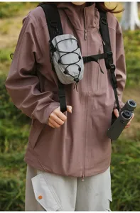 Detailopname van een grijze tactische tas bevestigd aan een outdoor jas schouderband.