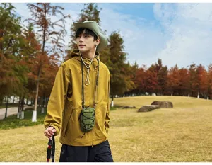 Model met een groene tactische mini-crossbodytas voor telefoons in een buitenomgeving