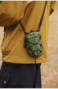 Detailopname van een groene tactische mini-schoudertas gedragen door een outdoorfan