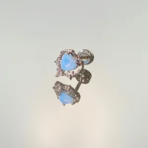 Macro view showing a silver heart-shaped stud earring with light blue opal and rhinestones