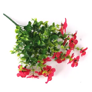 Close-up of vibrant red artificial flowers with green eucalyptus leaves on white